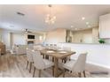 Bright dining room with modern chandelier, wood floors, and a view to the living area at 1512 Groom Ave, North Las Vegas, NV 89081