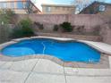 Inviting backyard pool featuring a unique shape, tiled border, and surrounding concrete patio at 533 Via Santiago St, Las Vegas, NV 89144