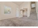 Bright living room boasts soaring ceilings, neutral-colored carpet, and a staircase leading upstairs at 6804 Tropicaire St, Las Vegas, NV 89149