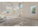 Spacious living room with a staircase, neutral-colored carpet, and sunlit windows overlooking the neighborhood at 6804 Tropicaire St, Las Vegas, NV 89149