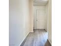 Hallway featuring neutral walls and modern gray wood-look floors, leading to a bright entry door at 7469 Margollini St, Las Vegas, NV 89148