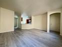 Spacious open-concept living area with gray wood-look floors flowing into the adjacent dining and kitchen spaces at 7469 Margollini St, Las Vegas, NV 89148