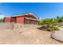 View of back of home with red siding and stone facade in backyard featuring desert landscaping at 812 Pyramid Dr, Las Vegas, NV 89107
