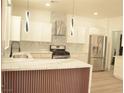 Bright kitchen with stainless steel appliances, custom cabinets, marble countertops, a unique backsplash, and an eye-catching island at 825 Cornerstone Pl, North Las Vegas, NV 89031