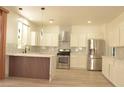 Modern kitchen featuring stainless steel appliances, white cabinetry, stylish backsplash, and a unique island design at 825 Cornerstone Pl, North Las Vegas, NV 89031