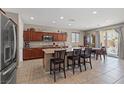 Spacious kitchen featuring granite countertops, dark wood cabinets, stainless steel appliances, and island seating at 8925 Kenzie Cove St, Las Vegas, NV 89131