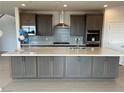 Open concept kitchen with large island, gray cabinetry, stainless appliances and tile backsplash at 9476 Lunar Phase St, Las Vegas, NV 89143