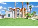 Two-story home featuring desert landscaping with tall palm trees on a green lawn at 2131 Diamond Bar Dr, Las Vegas, NV 89117