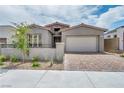 Charming single-story home featuring a well-manicured lawn, neutral tones, and a brick driveway leading to the garage at 2194 Pigeon Hawk St, Las Vegas, NV 89138