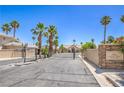 Gated community entrance to Canyon View Estates featuring a secure black gate, desert landscaping, and mature palm trees at 2201 Country Cottage Ct, Las Vegas, NV 89117