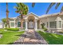 Elegant home featuring a well-manicured lawn, arched entryway, and a tiled roof, complimented by mature landscaping at 2201 Country Cottage Ct, Las Vegas, NV 89117