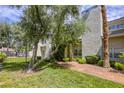 Inviting exterior view with lush green lawn, mature trees, and desert landscaping at 6250 W Flamingo Rd # 43, Las Vegas, NV 89103