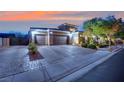 Home exterior with a three-car garage, desert landscaping, and brick paver driveway at 7300 Fresh Harvest Ave, Las Vegas, NV 89131