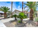 Single-story home featuring desert landscaping, lush palm trees and a white two-car garage at 7865 March Brown Ave, Las Vegas, NV 89149