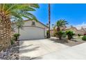 Single-story home showcasing desert landscaping, healthy palm trees and a white two-car garage at 7865 March Brown Ave, Las Vegas, NV 89149