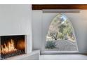 Cozy living room featuring a modern fireplace with stone accents and a unique arched window with garden view at 945 Vegas Valley Dr, Las Vegas, NV 89109
