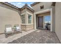 Inviting entrance featuring a tiled front patio and seating, with a view of the home's front door and a side window at 7258 W Le Baron Ave, Las Vegas, NV 89178