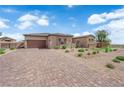Charming single-story home featuring desert landscaping, stone accents, brick driveway, and a neutral color palette at 7258 W Le Baron Ave, Las Vegas, NV 89178