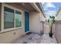 Charming side entry with teal door and paver flooring, complemented by a potted plant and wrought iron gate at 7616 Quail Dust St, North Las Vegas, NV 89084