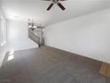 A spacious living room with gray carpet, a ceiling fan, lots of light, and stairs leading to the 2nd story at 8253 Pearl Oasis Ct, Las Vegas, NV 89139