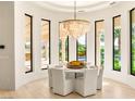 Elegant dining room with a stunning chandelier and views of the pool and lush landscaping at 8895 S Tenaya Way, Las Vegas, NV 89113