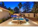 A pristine hot tub on a stone patio, surrounded by manicured landscaping and ambient lighting at 1990 Freeman Ct, Henderson, NV 89014