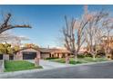 Attractive single-story brick home featuring a driveway, manicured lawn, and lush landscaping at 3104 Conners Dr, Las Vegas, NV 89107