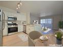 A modern kitchen features white cabinets, stainless steel appliances, and a cozy dining area at 5710 E Tropicana Ave # 1018, Las Vegas, NV 89122