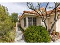 Charming front exterior featuring desert landscaping, privacy bush, and a tile roof at 1632 Royal Canyon Dr, Las Vegas, NV 89128