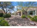 Relaxing backyard space featuring desert landscaping, shade trees, and a covered patio area perfect for entertaining at 2467 Moonlight Valley Ave, Henderson, NV 89044