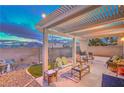 Relaxing covered patio with comfortable seating, a grill, and a view of the landscaped backyard at 2595 Amber Crest St, Las Vegas, NV 89142