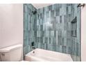 Bathroom featuring modern fixtures, tub with shower, and blue vertical tiling at 1600 E Mcdonald Ave, North Las Vegas, NV 89030