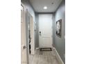 A hallway with a white front door and gray walls, complemented by light wood-look flooring at 23 E Agate Ave # 301, Las Vegas, NV 89123