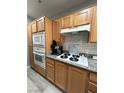A functional kitchen featuring wood cabinetry, white appliances, and a gas cooktop at 23 E Agate Ave # 301, Las Vegas, NV 89123
