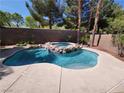 Backyard oasis featuring a sparkling pool with a rock-enclosed hot tub and mature landscaping at 23 Indian Run Way, Las Vegas, NV 89148