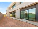 A modern home's backyard featuring pavers, a minimalist landscape, and expansive sliding glass doors at 25 Canyon Bay Dr, Henderson, NV 89011
