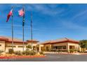 A clubhouse with beautiful landscaping under a bright blue sky with the American flag at 3124 Kookaburra Way, North Las Vegas, NV 89084