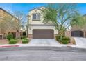 Traditional home with a two-car garage, complemented by mature trees and manicured shrubs at 3712 Gilmore Creek St, Las Vegas, NV 89129