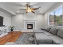 Bright living room featuring a cozy fireplace, hardwood floors, and a ceiling fan at 644 Wind Cave Ct, Henderson, NV 89012