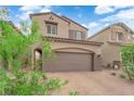 Two-story home featuring a brick driveway and two-car garage, complemented by desert landscaping and a blue sky at 872 Pointe Arbor St, Henderson, NV 89011