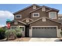 A tan two-story home features a two-car garage and desert landscaping at 9145 Sunken Meadow Ave, Las Vegas, NV 89178