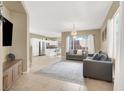 Open living space with tile flooring, neutral walls, and comfortable seating next to the kitchen at 9869 Lime Tree St, Las Vegas, NV 89178