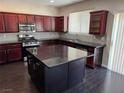 Open kitchen with large island, granite counters, stainless appliances and dark wood cabinets at 10118 Farmington Hall Ct, Las Vegas, NV 89129
