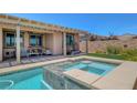 Gorgeous backyard oasis featuring a sparkling pool and spa with a covered patio area at 1120 Via Della Curia, Henderson, NV 89011