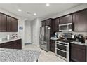 Well-equipped kitchen with stainless steel appliances, dark wood cabinets, and stylish countertops at 1266 Smokey Valley Ln, Henderson, NV 89002