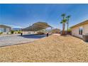 Gravel backyard featuring a covered structure with a patio and palm trees at 2851 Winchester Ave, Pahrump, NV 89048
