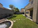 Backyard featuring an artificial stream surrounded by green grass, stepping stones and privacy fence at 7821 Red Leaf Dr, Las Vegas, NV 89131