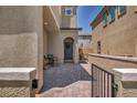 Inviting front porch featuring brick pavers, a wrought iron gate, and cozy seating area at 8055 Tank Loop St, Las Vegas, NV 89166