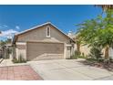 View of the home's exterior, featuring a two-car garage and desert landscaping in the front yard at 8242 Tribute Ln, Las Vegas, NV 89147