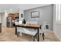 Well-lit dining area with a wooden table, cushioned bench, stylish chairs, and modern decor against gray walls at 9208 S Park St, Las Vegas, NV 89178